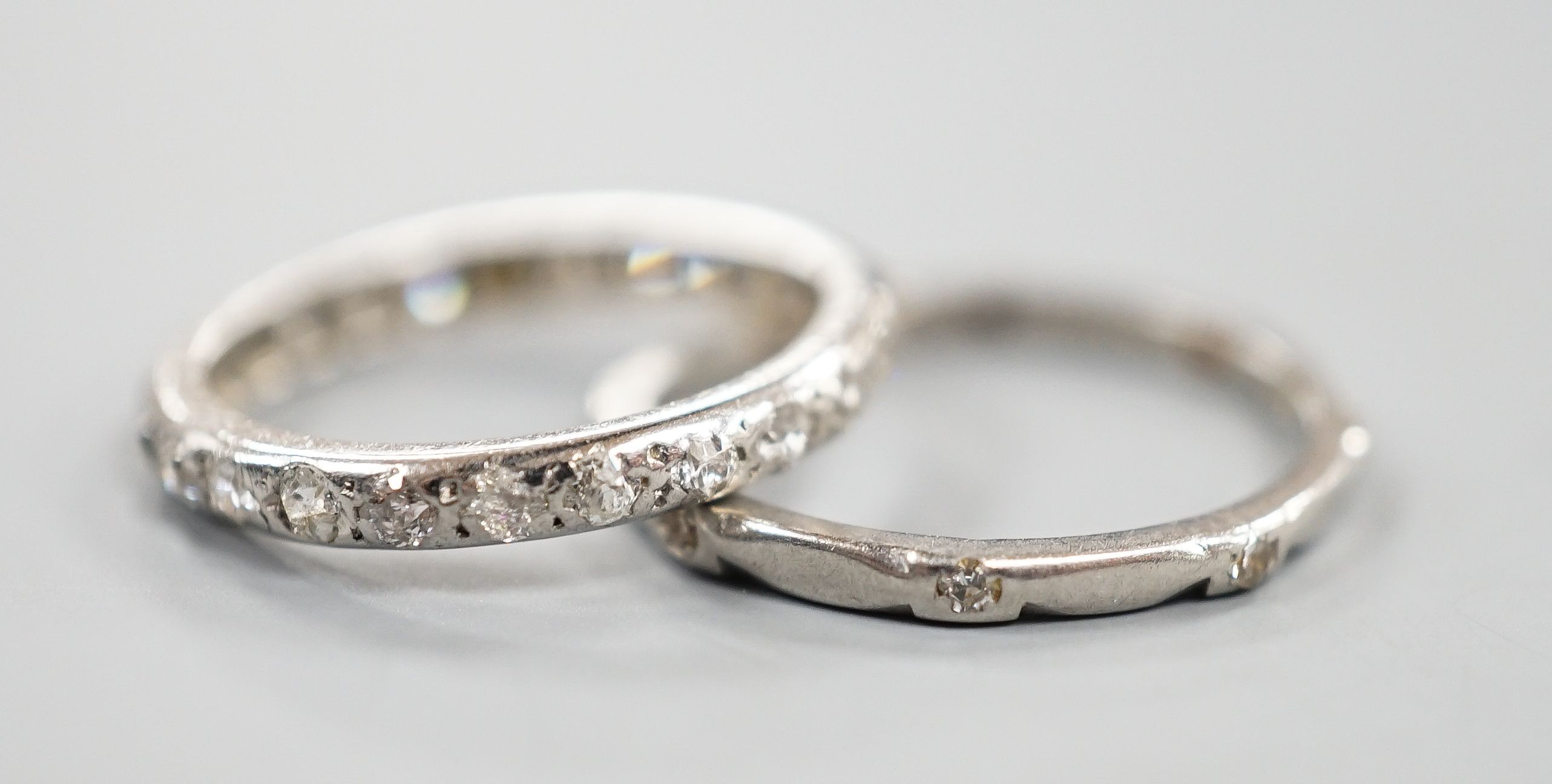 A white metal and diamond chip set full eternity ring, size J and a white metal (stamped Pt) and diamond set eternity ring (two stones missing), size L, gross weight 4.2 grams.